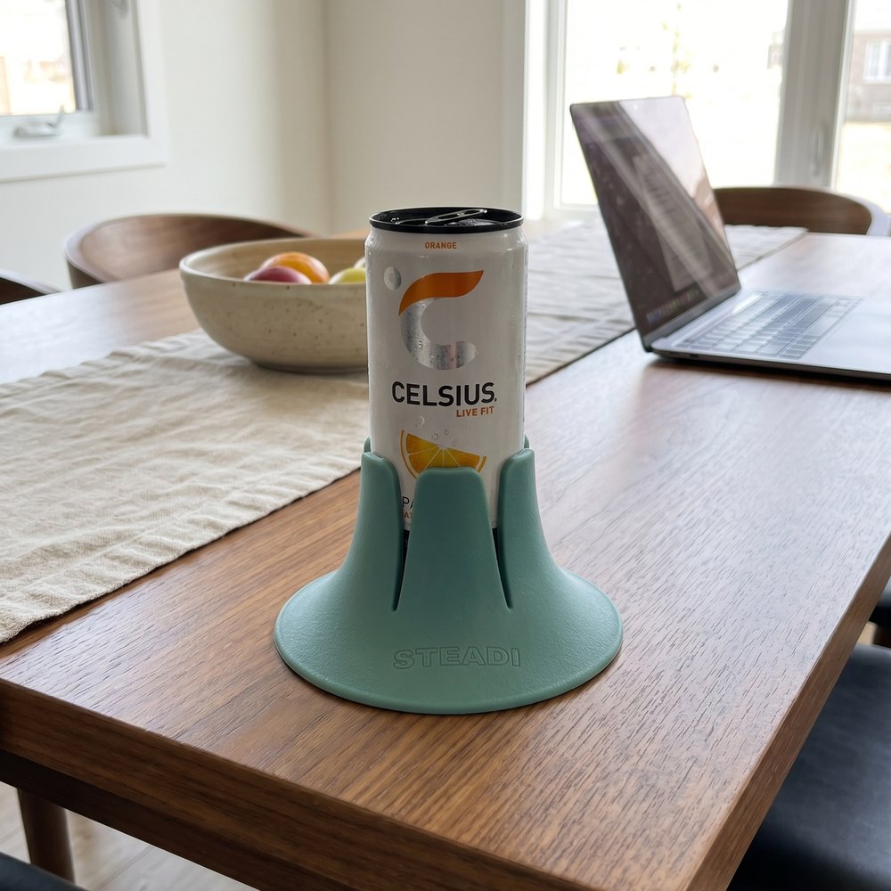 A can standing in a sage Steadi on a wooden table beside a window.